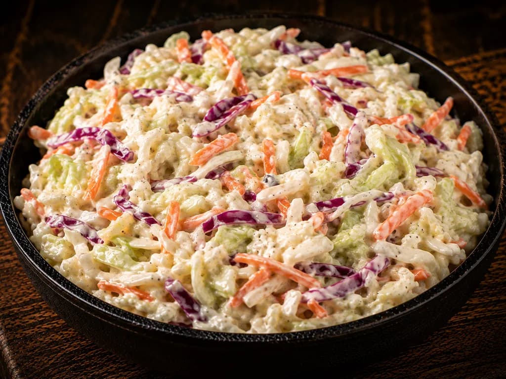 A bowl of creamy coleslaw made with green and red cabbage and shredded carrot